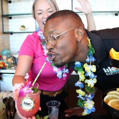 Tony performing a playful drink moment with Mariel behind him